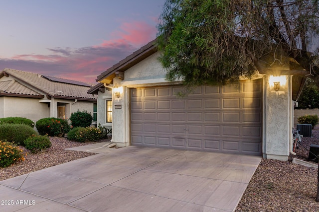 view of front of property with a tile roof, central AC unit, driveway, an attached garage, and stucco siding