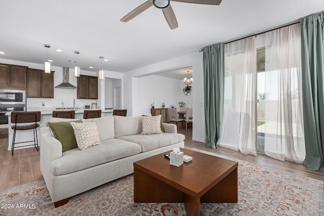 living room featuring light hardwood / wood-style flooring, ceiling fan with notable chandelier, and sink