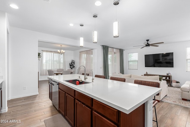 kitchen featuring sink, ceiling fan with notable chandelier, decorative light fixtures, and a center island with sink