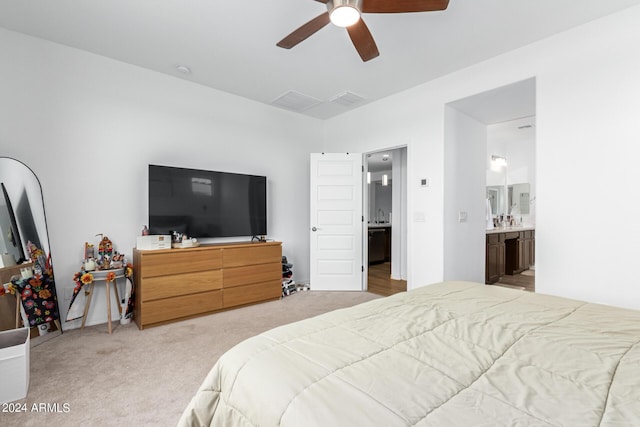 carpeted bedroom with ensuite bath and ceiling fan