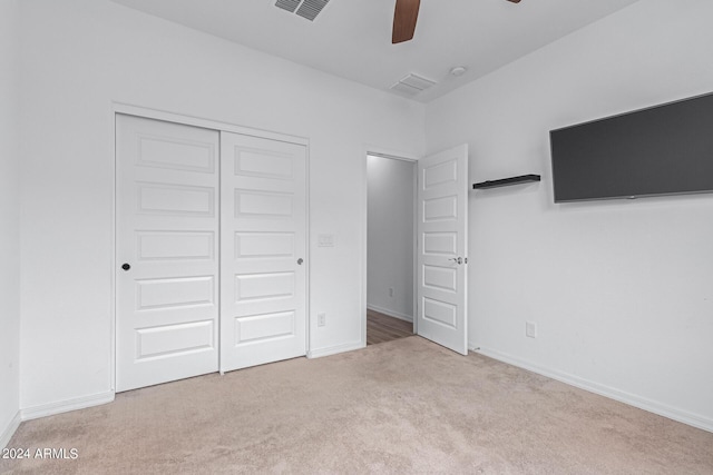 unfurnished bedroom featuring ceiling fan, light carpet, and a closet