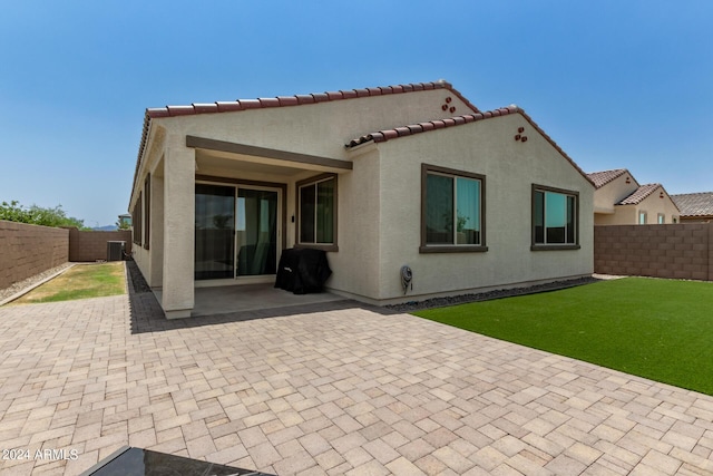 rear view of house with a lawn and a patio