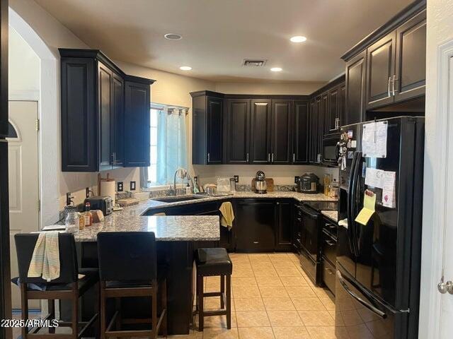 22744 E Carla Vista Dr, Mesa, AZ 85212 - kitchen featuring light stone counters, a sink, black appliances, a kitchen bar, and a peninsula