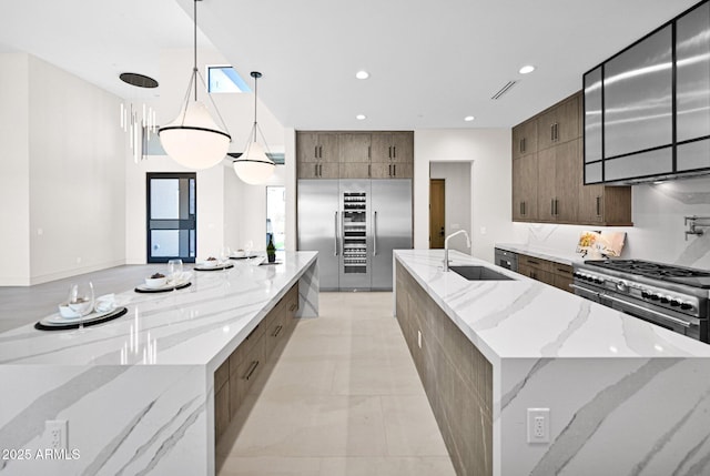 kitchen featuring recessed lighting, a large island with sink, a sink, modern cabinets, and premium appliances