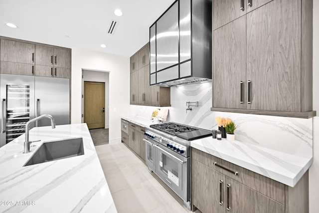 kitchen with range hood, high quality appliances, modern cabinets, and a sink