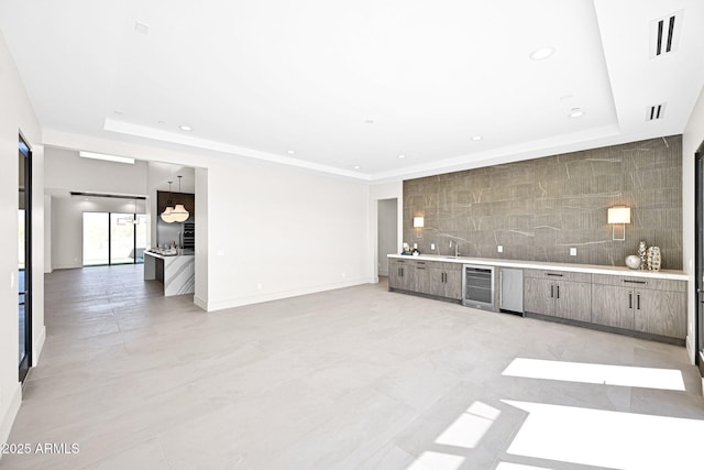 unfurnished living room with wine cooler, recessed lighting, wet bar, and a raised ceiling