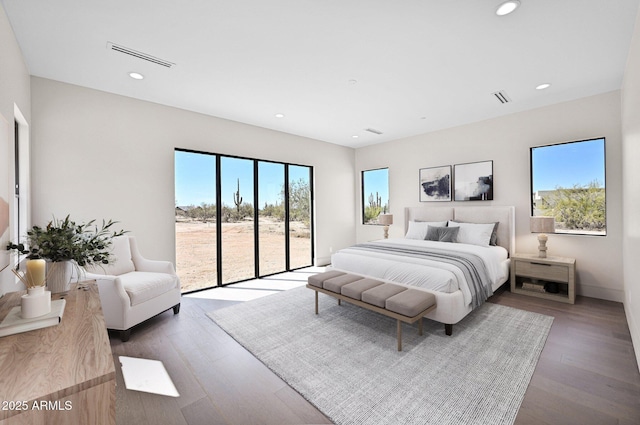 bedroom with visible vents, wood finished floors, and access to exterior