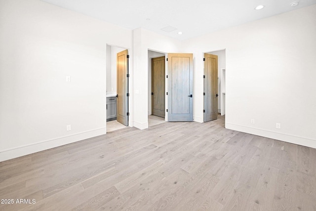 unfurnished bedroom featuring recessed lighting, light wood-type flooring, baseboards, and ensuite bath