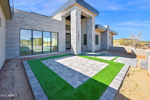 rear view of property featuring a patio area and stone siding