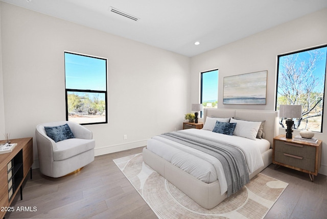 bedroom featuring light wood finished floors, visible vents, recessed lighting, and baseboards