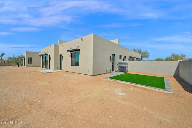 back of property with stucco siding and fence private yard