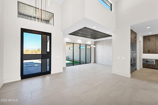 entryway featuring recessed lighting, baseboards, and a towering ceiling