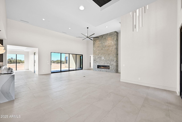 unfurnished living room featuring recessed lighting, a fireplace, baseboards, and a towering ceiling