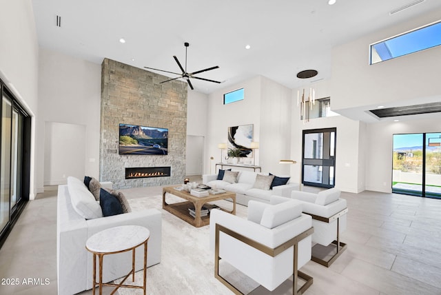 living area featuring recessed lighting, a stone fireplace, a towering ceiling, and a ceiling fan