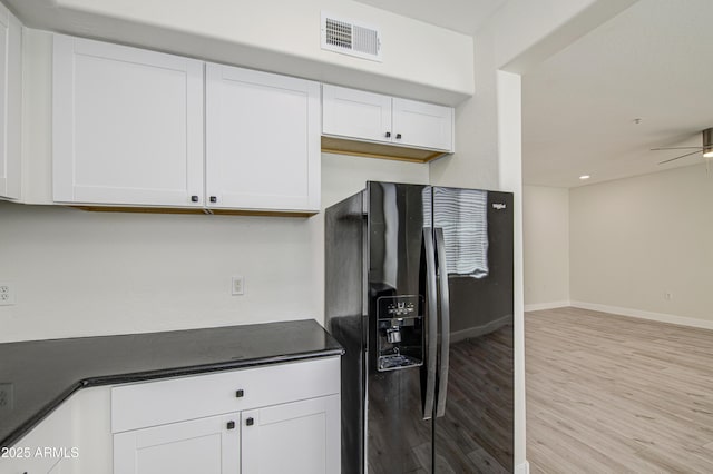 615 E Portland St Unit 261, Phoenix, AZ 85004 - kitchen with black fridge, dark countertops, light wood finished floors, white cabinets, and a ceiling fan