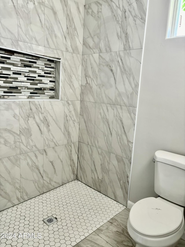 bathroom with a tile shower and toilet