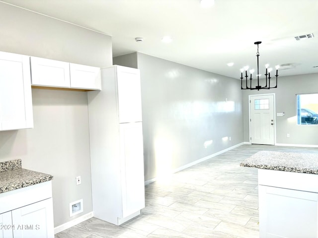 kitchen featuring pendant lighting, stone countertops, white cabinetry, and a chandelier