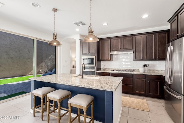 3910 E Turley St, Gilbert, AZ 85295 - kitchen with appliances with stainless steel finishes, light tile patterned floors, dark brown cabinetry, light stone counters, and backsplash