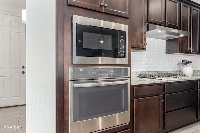 3910 E Turley St, Gilbert, AZ 85295 - kitchen featuring appliances with stainless steel finishes, light tile patterned floors, dark brown cabinets, backsplash, and under cabinet range hood