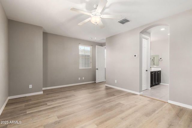 3910 E Turley St, Gilbert, AZ 85295 - unfurnished bedroom featuring arched walkways, light wood finished floors, baseboards, connected bathroom, and ceiling fan