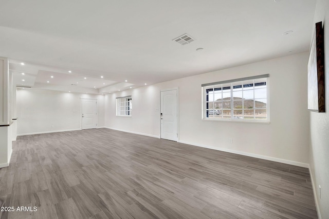 empty room with baseboards, visible vents, wood finished floors, and recessed lighting