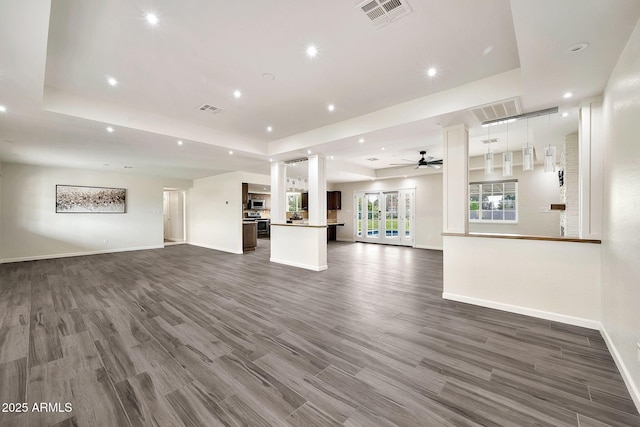 unfurnished living room featuring visible vents, a raised ceiling, and wood finished floors