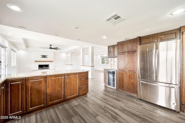 kitchen with a large fireplace, visible vents, wine cooler, dark wood-style flooring, and freestanding refrigerator