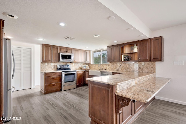 kitchen with tasteful backsplash, visible vents, appliances with stainless steel finishes, a peninsula, and open shelves