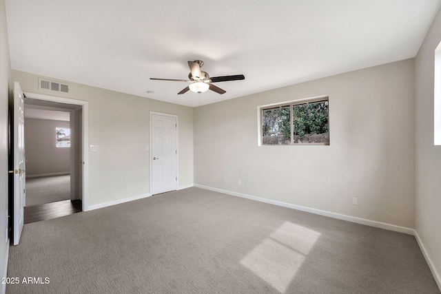 unfurnished bedroom featuring visible vents, dark carpet, baseboards, and ceiling fan