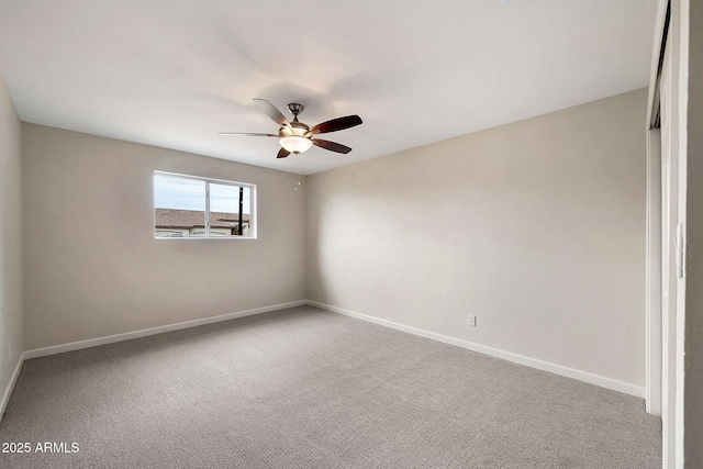 carpeted spare room featuring ceiling fan and baseboards