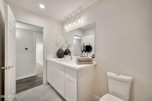 half bath with toilet, baseboards, and vanity