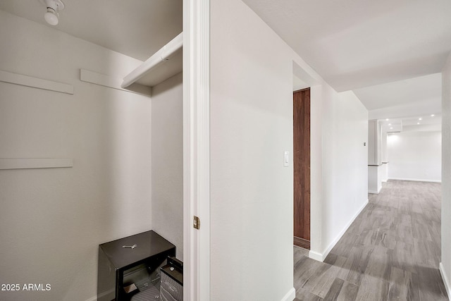 corridor with baseboards and wood finished floors