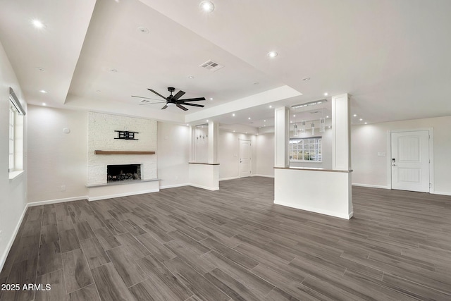 unfurnished living room featuring a stone fireplace, recessed lighting, wood finished floors, visible vents, and a tray ceiling