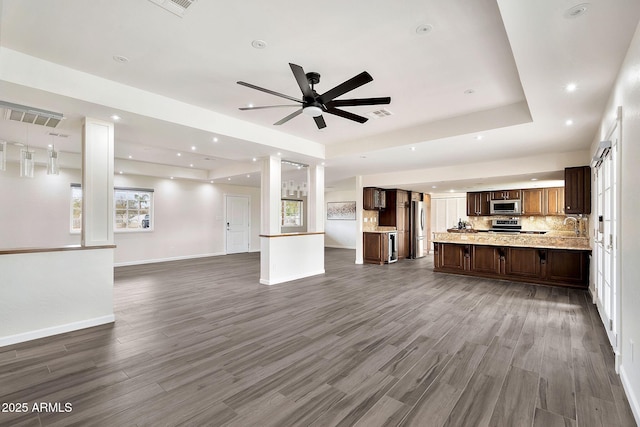 unfurnished living room featuring wood finished floors, a raised ceiling, a ceiling fan, and baseboards