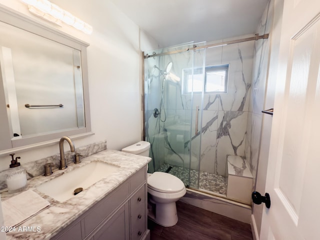 bathroom with walk in shower, vanity, wood-type flooring, and toilet