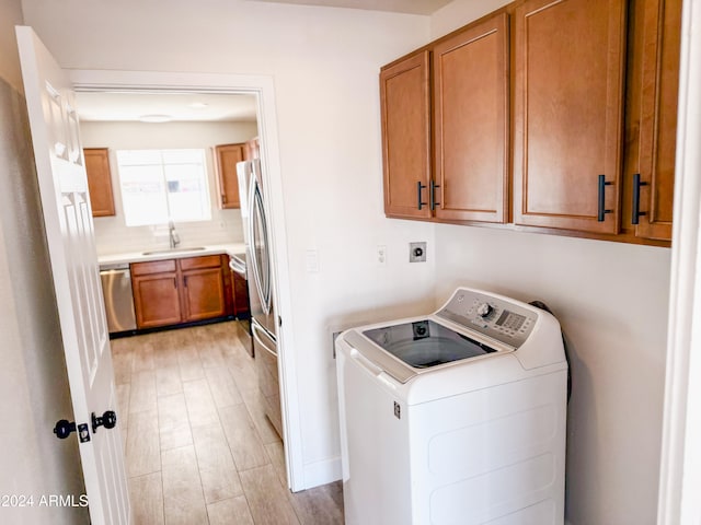 laundry room featuring cabinets, light hardwood / wood-style floors, washer / dryer, and sink