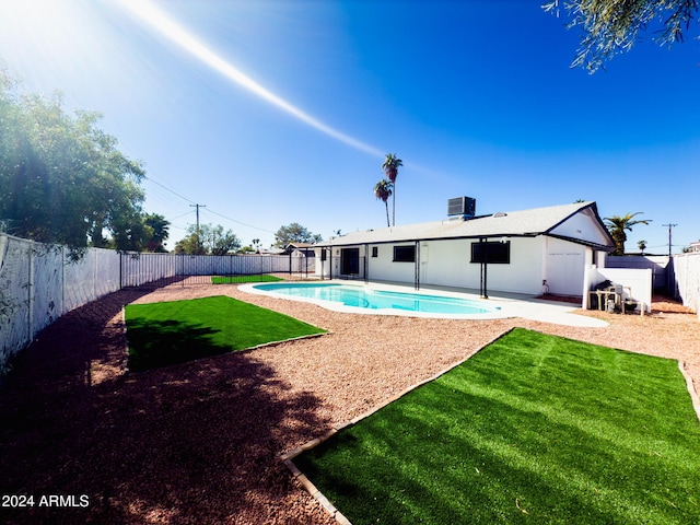 view of swimming pool with central air condition unit, a patio area, and a lawn