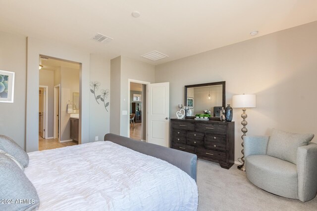 bedroom with light carpet, ensuite bath, and visible vents