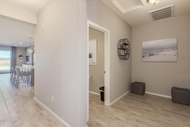 corridor with light wood-style flooring, visible vents, and baseboards