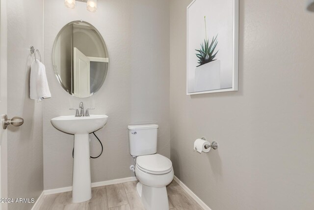 bathroom featuring baseboards, toilet, and wood tiled floor