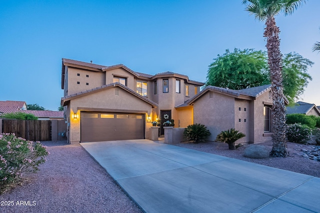 view of front facade featuring fence, stucco siding, concrete driveway, an attached garage, and a tile roof