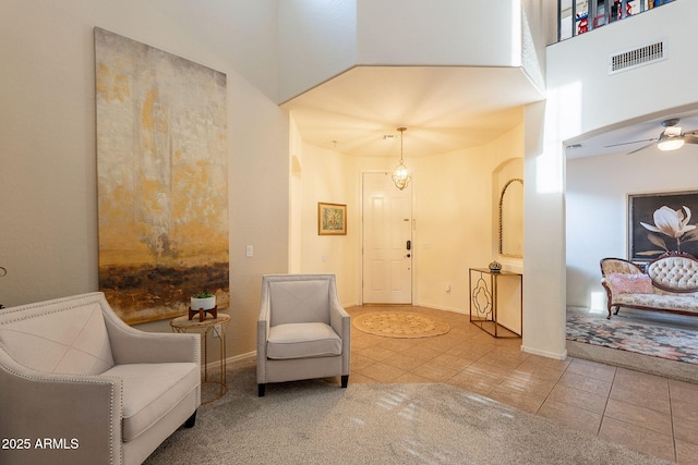 sitting room featuring visible vents, baseboards, ceiling fan, a high ceiling, and tile patterned floors