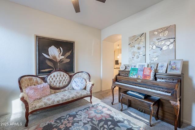 living area with arched walkways, ceiling fan, baseboards, and carpet