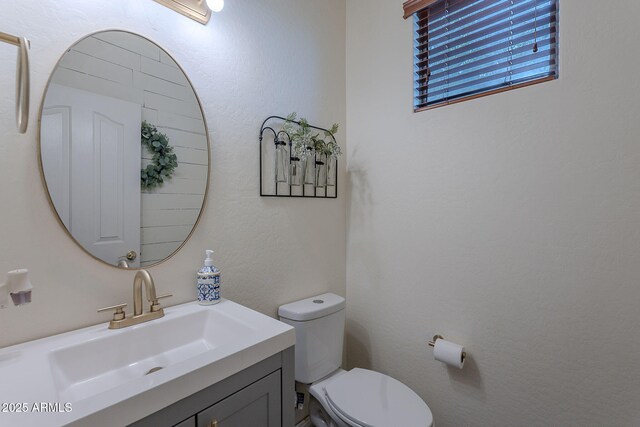 half bathroom featuring vanity and toilet