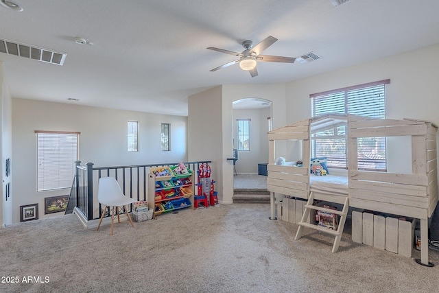 rec room with visible vents, arched walkways, carpet floors, and ceiling fan