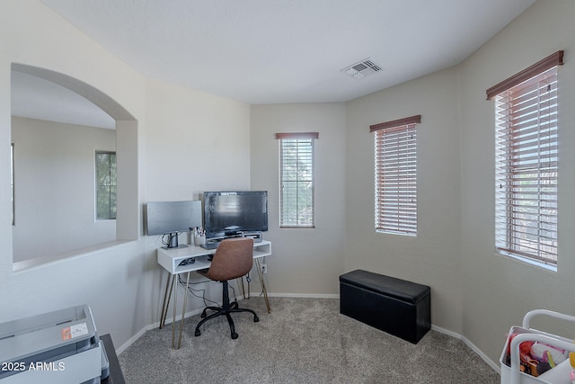 carpeted home office featuring arched walkways, baseboards, and visible vents