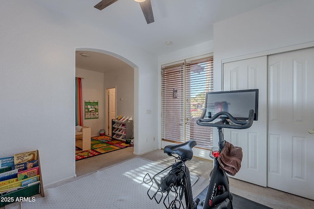 workout room featuring arched walkways, carpet, and a ceiling fan
