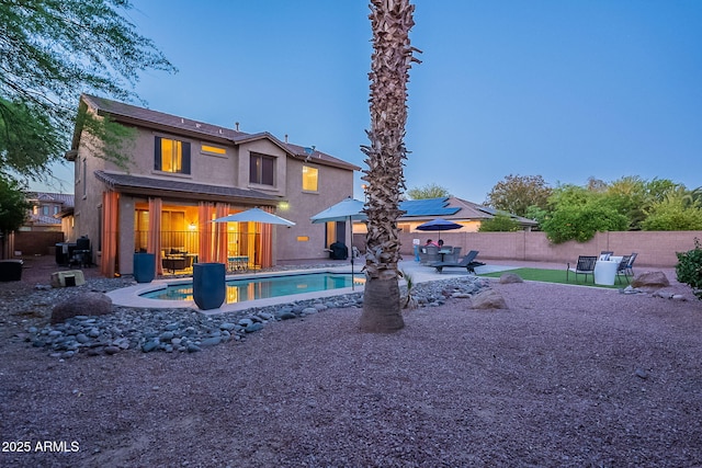 rear view of house featuring a fenced backyard, a fenced in pool, a patio, and stucco siding