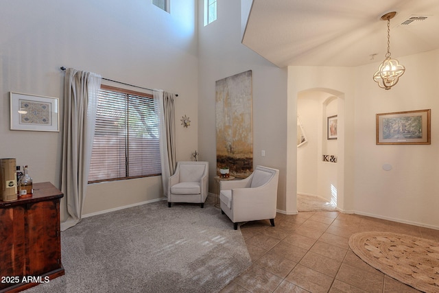 living area featuring visible vents, an inviting chandelier, baseboards, tile patterned floors, and arched walkways