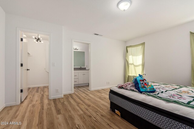 bedroom with a chandelier, light hardwood / wood-style flooring, and ensuite bathroom